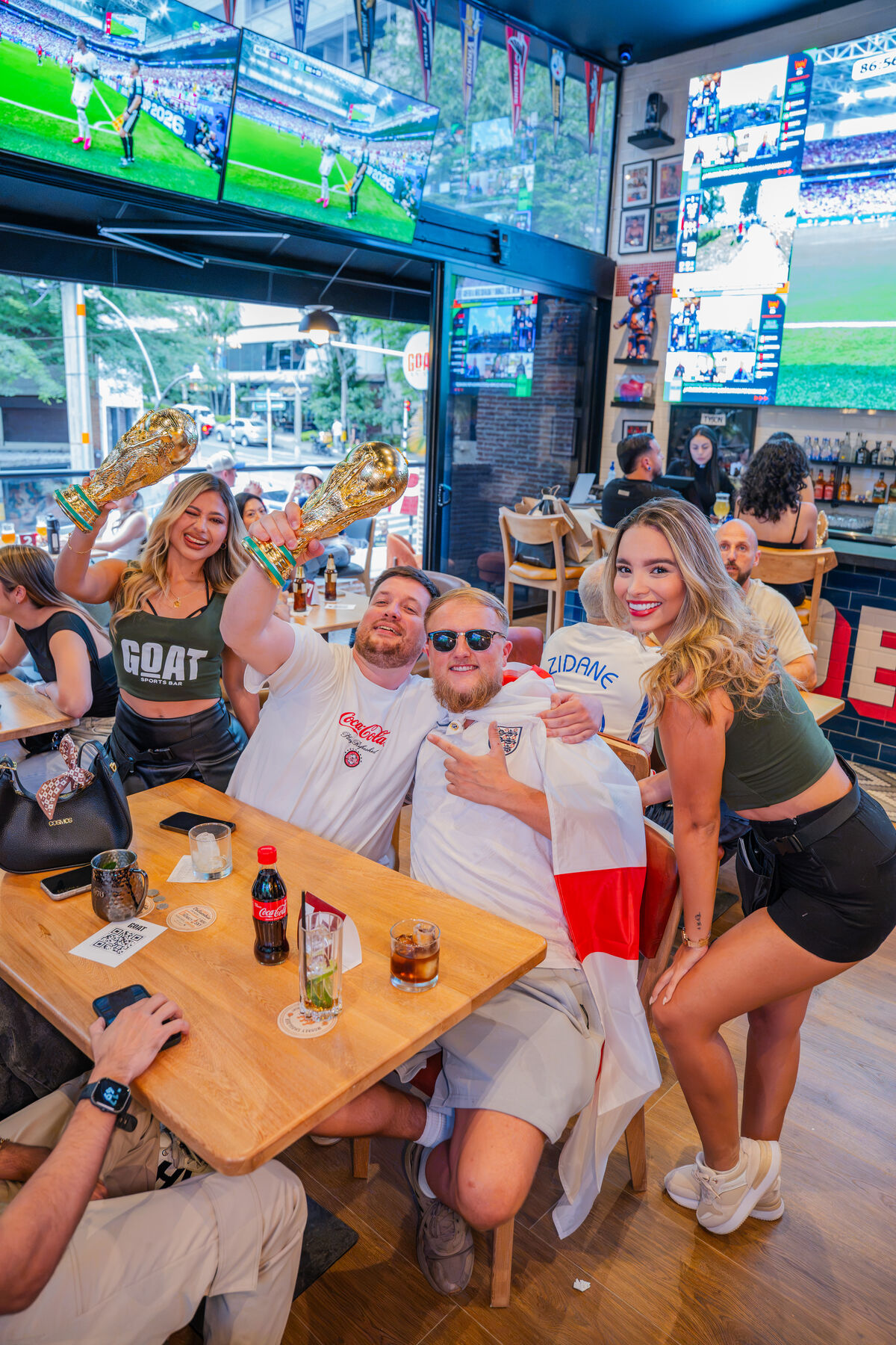Guests celebrating football match day at GOAT Sports Bar Medellín beneath multiple large screens